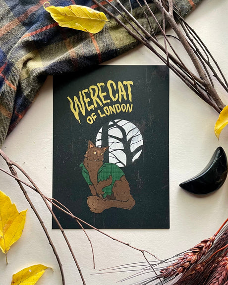 A horror-themed print featuring an illustration of a werecat (a cat with human-like features) in the middle of a forest, with a plaid background and autumnal leaves around it.