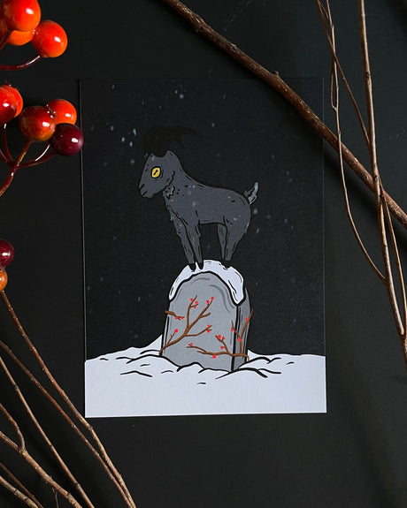 A black and white illustration of a goat standing on a grave with a snowy backdrop and a night sky in the background, with red berries and a branch in the foreground.