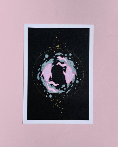 A 5x7 zodiac print featuring Pisces with a stylized graphic of two fish and a crescent moon on a dark background, placed against a pink background.