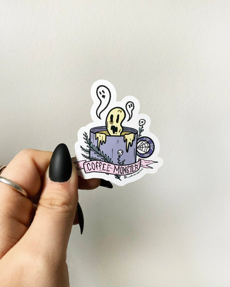 A vinyl sticker with a cartoon monster design, featuring a cup of coffee and the text 'COFFEE MONSTER'.