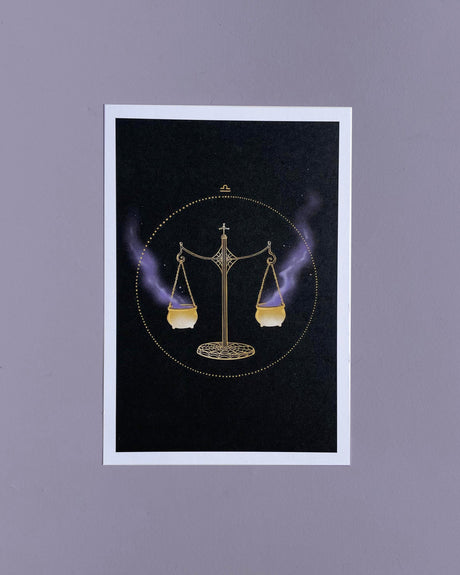 A 5x7 print of a hand drawn illustration featuring a balance scale with gold and purple colors, and two small magical cauldrons balanced on the scale with spider web details.