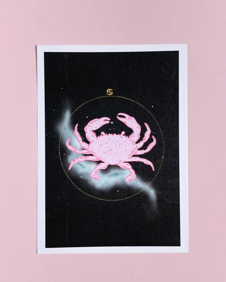 A 5x7 print of a hand drawn illustration of a pink crab with a stylized background, representing the Cancer Zodiac.
